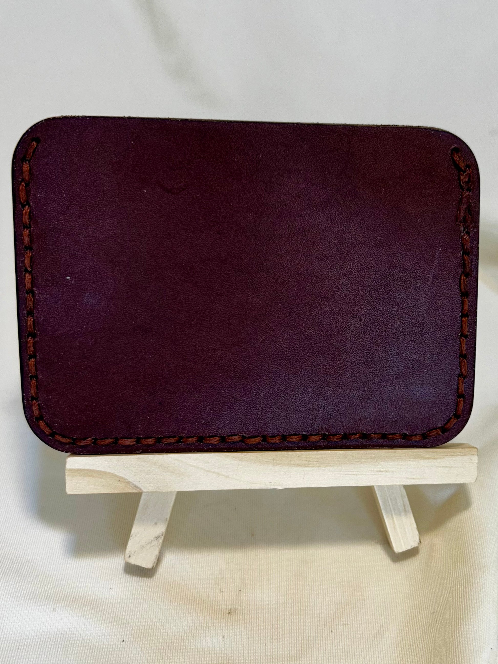 The back of a card holder wallet in brown leather with slightly lighter brown stitching 