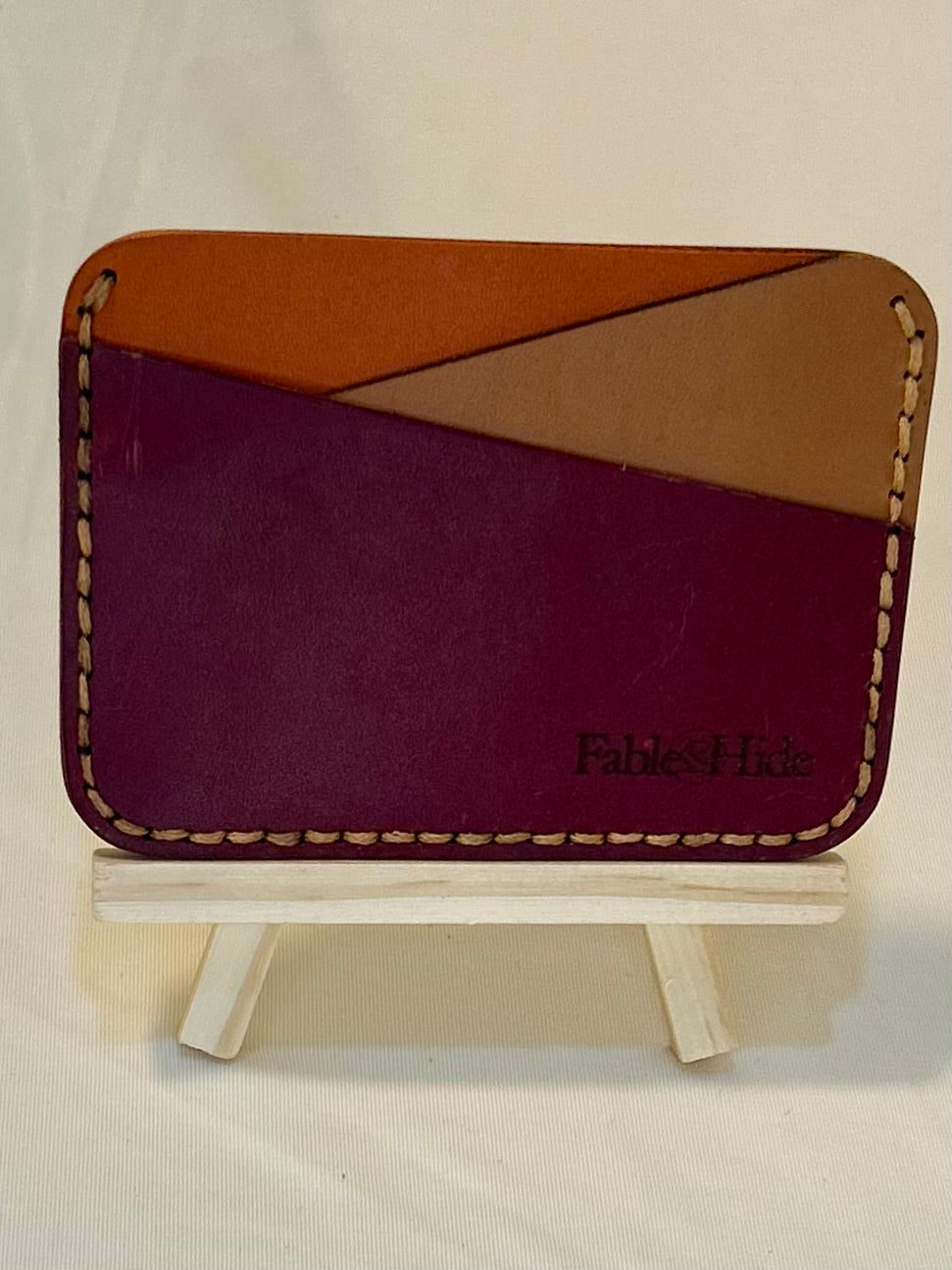 Tan, maroon, and orange card holder with tan stitching 