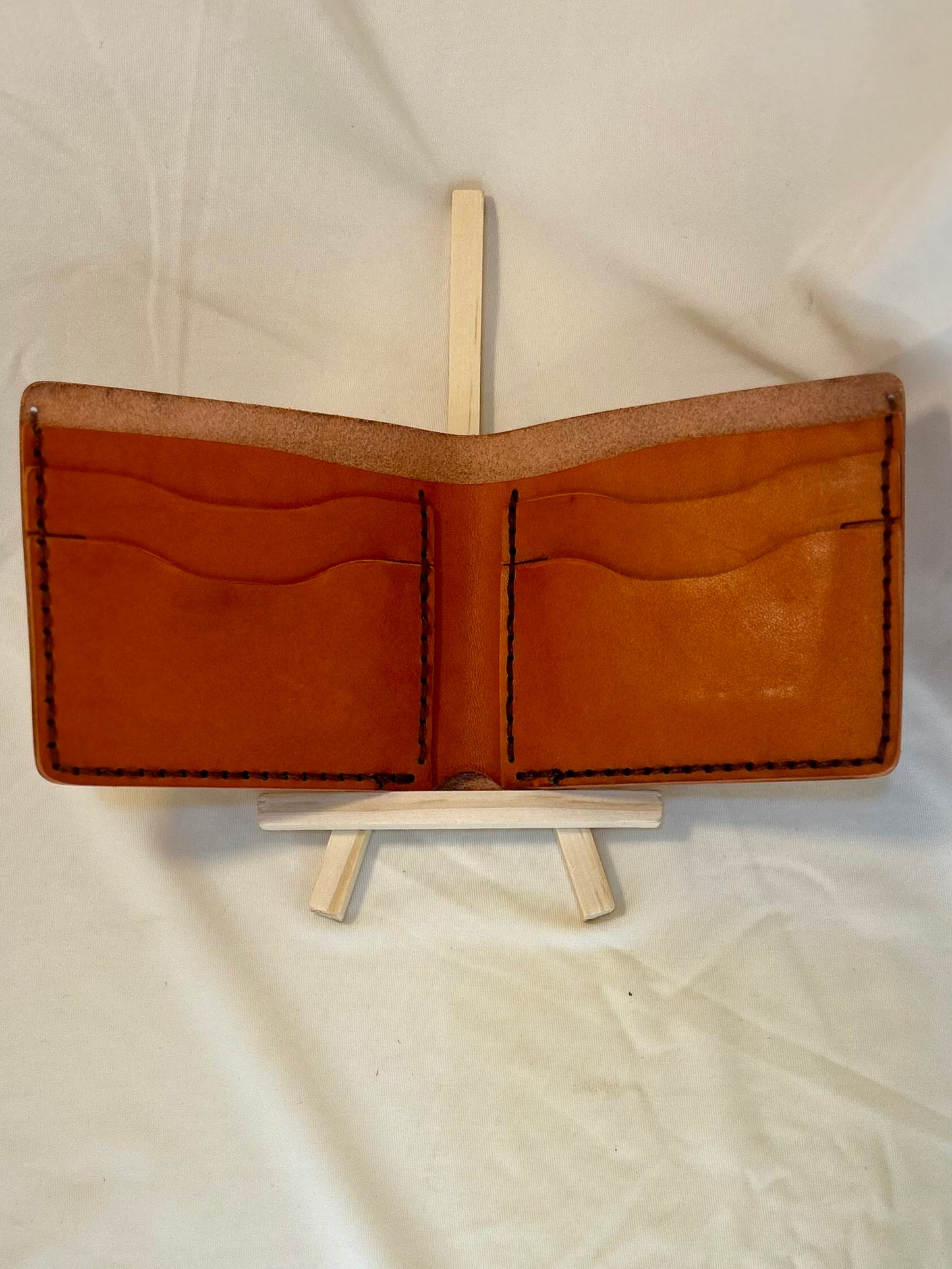 Inside of a wallet with orange pockets and brown stitching 