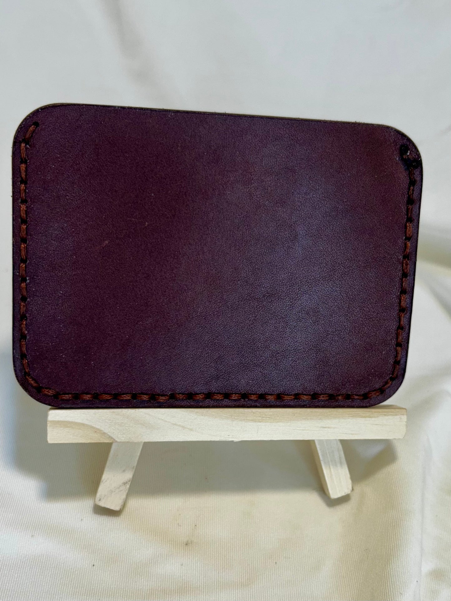 The back of a card holder wallet in brown leather with slightly lighter brown stitching 