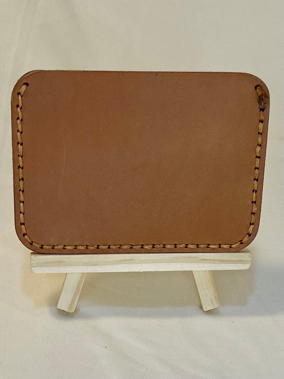 Back of a tan card holder with tan stitching 