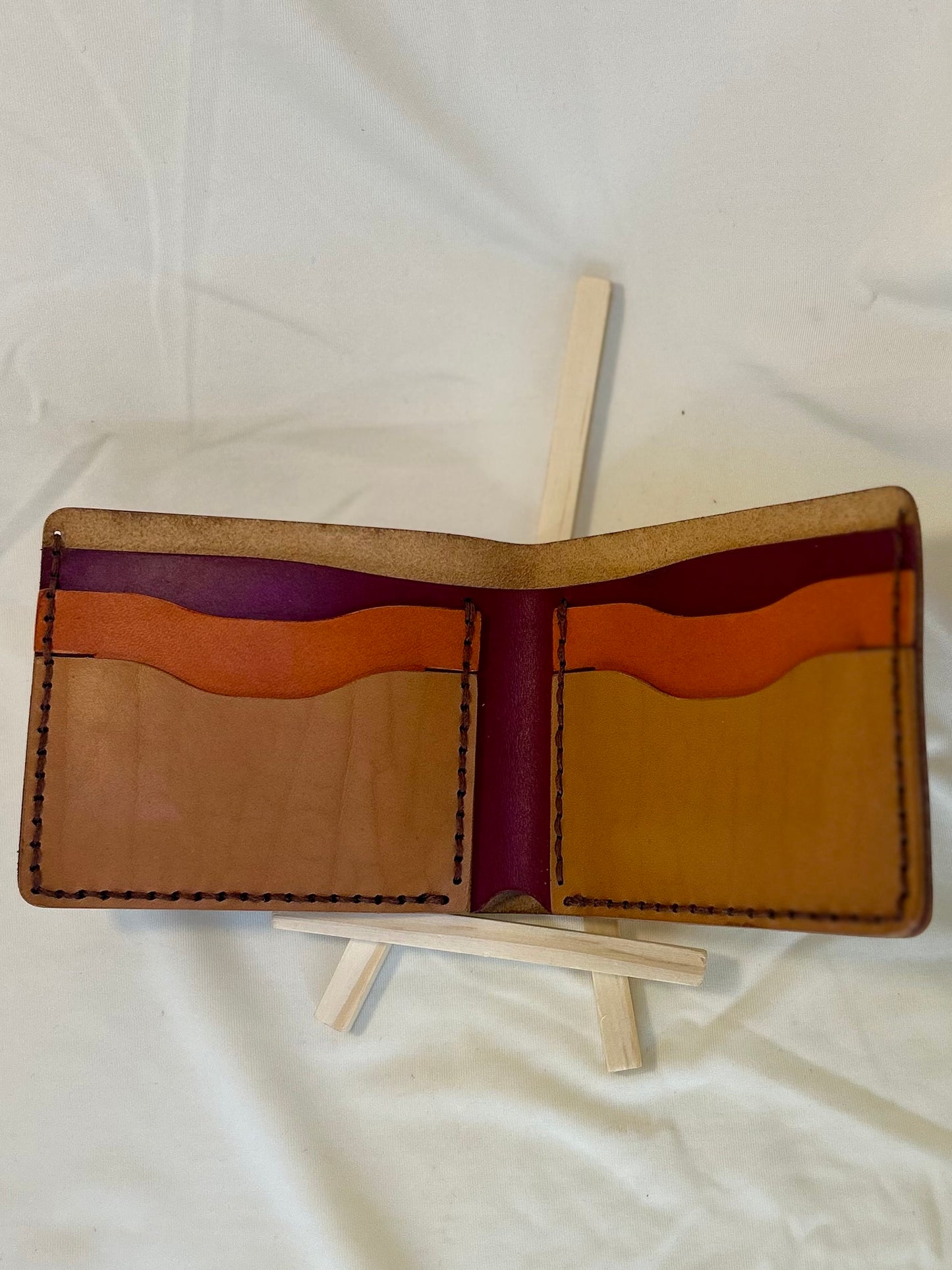 Inside of a wallet with orange, tan, and maroon pockets.